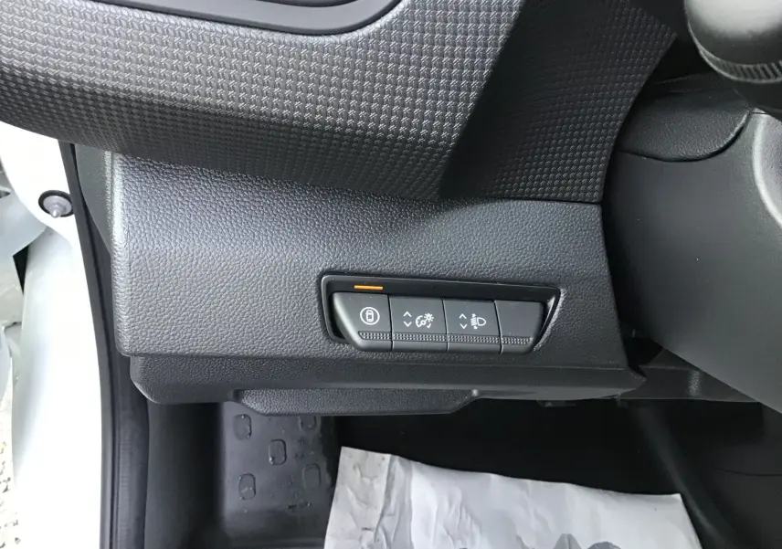 Gros plan sur les commandes de réglage d’éclairage et verrouillage, côté gauche du tableau de bord noir du Renault Trafic blanc.
