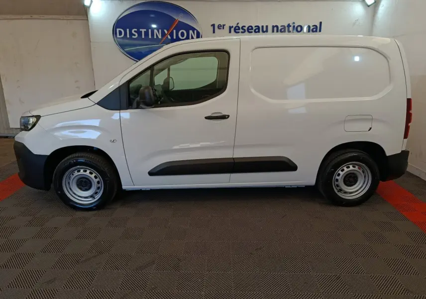 Peugeot Partner blanc en vue de profil côté gauche, utilitaire compact avec porte latérale pleine et jantes acier.