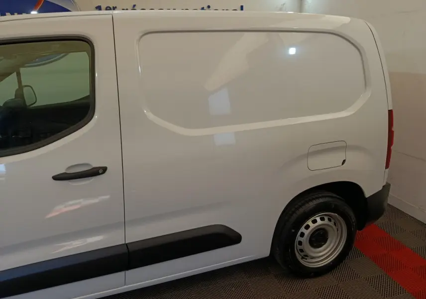 Vue latérale droite d’un utilitaire Peugeot Partner blanc, avec porte latérale pleine et jante acier simple.