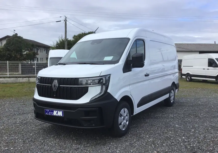 Renault Master blanc en vue 3/4 avant droit, avec calandre noire et pare-chocs noir mat sur terrain gravillonné.