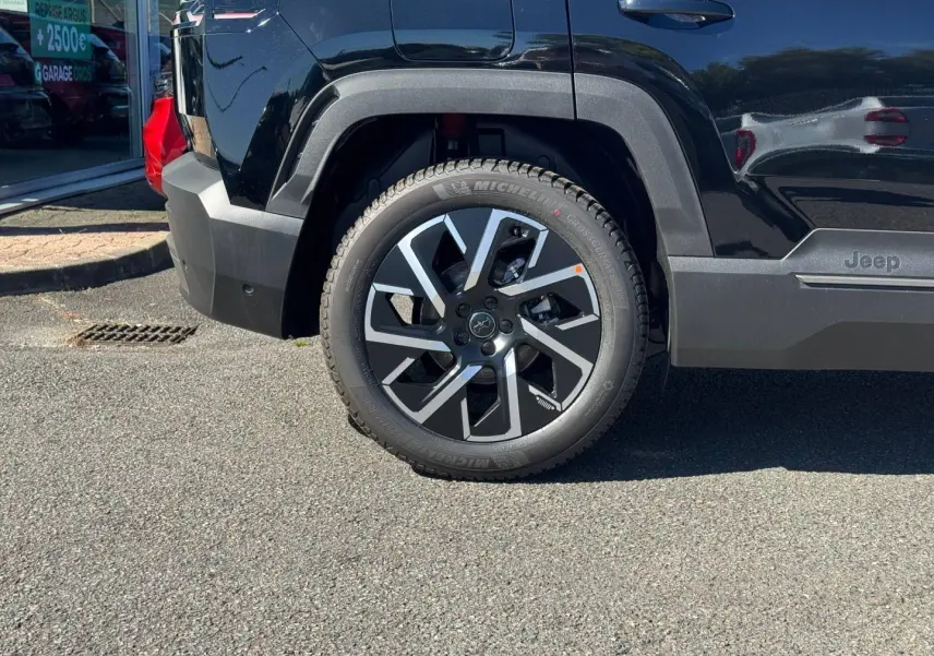 Gros plan sur la roue arrière droite d’un Jeep Compass Vulcano noir avec jante alu au design moderne.