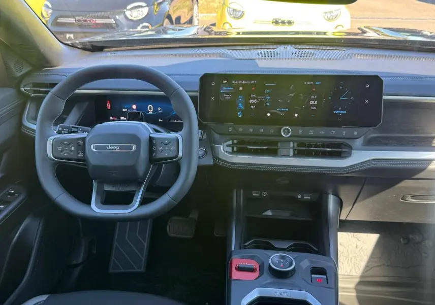 Vue intérieure avant du tableau de bord et volant Jeep Compass 2026 avec écran tactile large et commandes au volant.