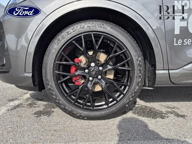 Gros plan sur la roue avant gauche du Ford Kuga gris métallisé avec jante noire et étrier de frein rouge.