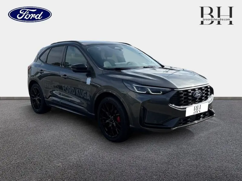 Ford Kuga gris métallisé vu en 3/4 avant droit avec jantes noires et calandre imposante noire brillante.