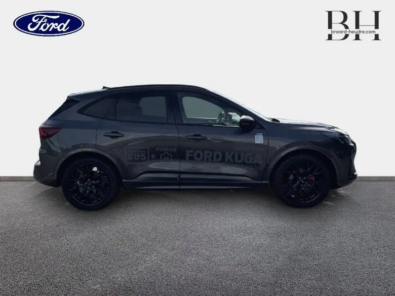 Profil droit du Ford Kuga 2025 gris Magnetic avec jantes noires et badges hybrides visibles sur la porte.