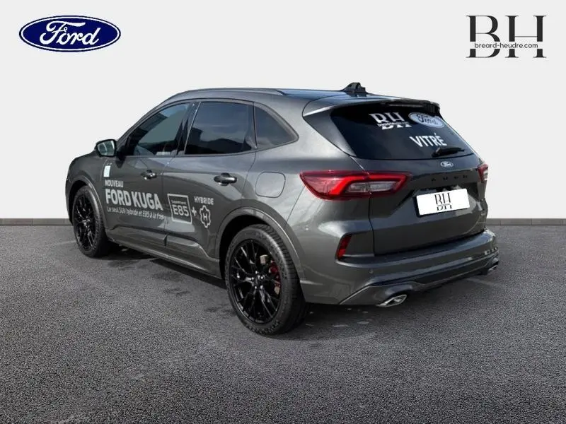 Vue 3/4 arrière droite d'un Ford Kuga gris métallisé avec jantes noires et marquages hybrides sur la portière.
