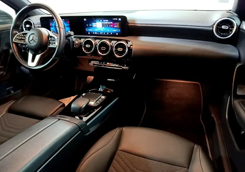 Vue intérieure côté conducteur de la Mercedes Classe A 180 d Business Line 2021 avec volant cuir et écran tactile double.