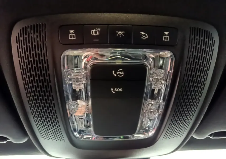Gros plan sur la console de toit noire avec boutons d'appel d'urgence et éclairage intérieur d'une Mercedes Classe A gris foncé.