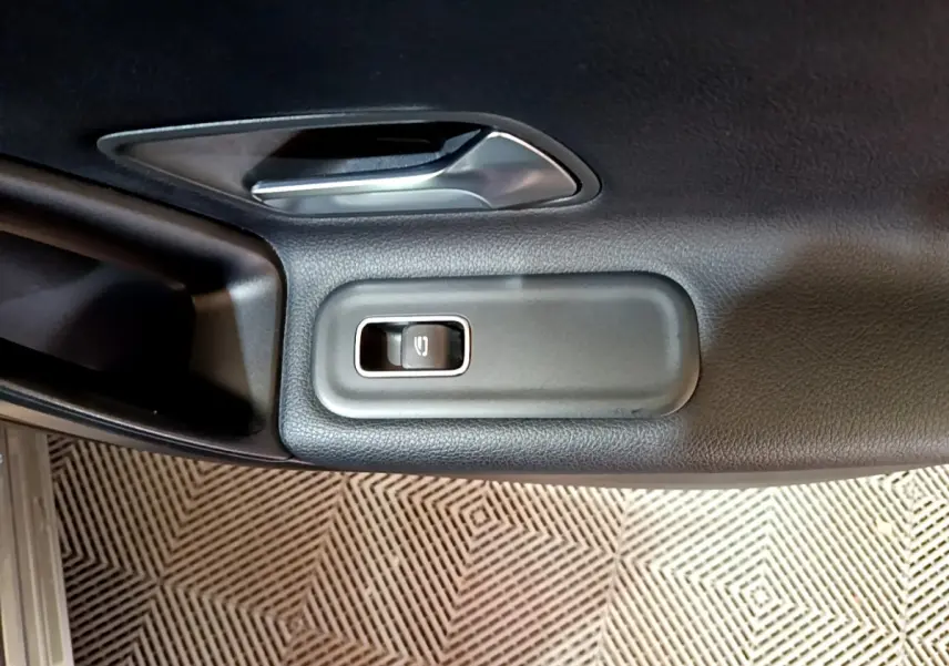 Détail de la commande de lève-vitre électrique sur la porte intérieure côté gauche d’une Mercedes Classe A gris foncé.