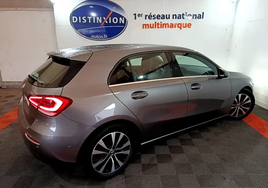 Mercedes Classe A 180 d Business Line gris foncé vue 3/4 arrière droit avec feux arrière allumés en intérieur.