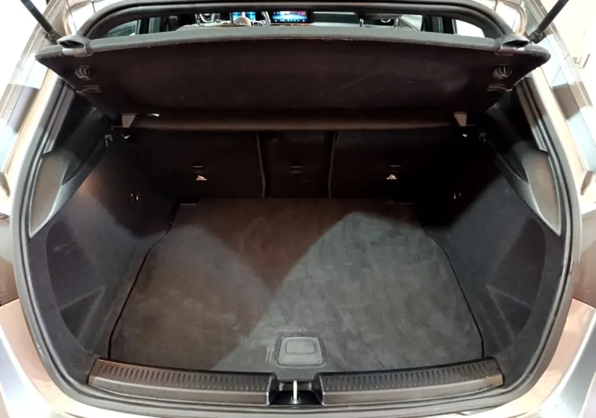 Coffre ouvert vu de l'arrière d'une Mercedes Classe A gris foncé, montrant l'espace de chargement vide.