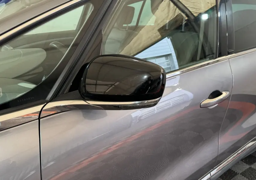 Rétroviseur noir en gros plan côté conducteur sur la porte gris foncé d’un Renault Espace 2015.