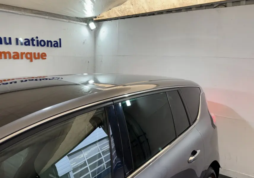 Vue côté droit arrière d’un Renault Espace gris foncé avec vitres arrière teintées dans un garage.