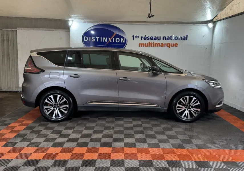 Profil droit d'un Renault Espace gris foncé 2015, avec jantes alliage bicolores et vitres teintées, en intérieur showroom.