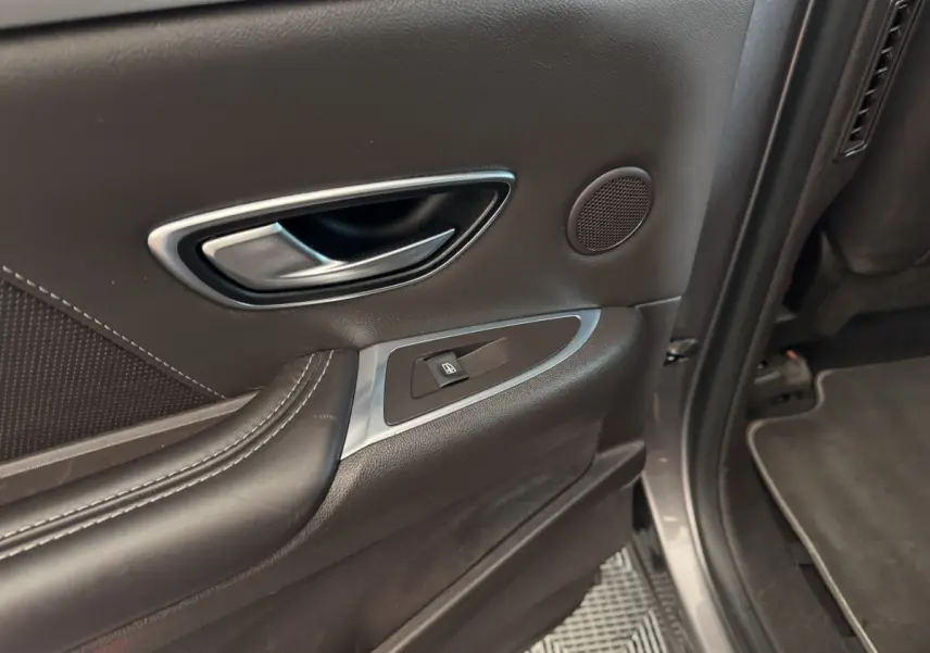 Gros plan sur la poignée intérieure et la commande de vitre côté arrière droit d'une Renault Espace gris foncé.