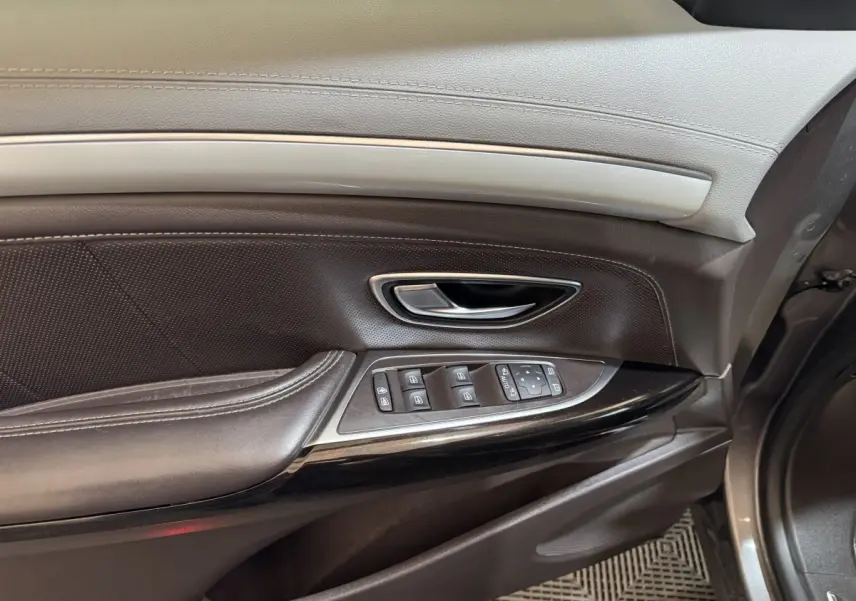 Gros plan sur la porte côté conducteur du Renault Espace gris foncé, montrant les commandes électriques et la poignée intérieure.