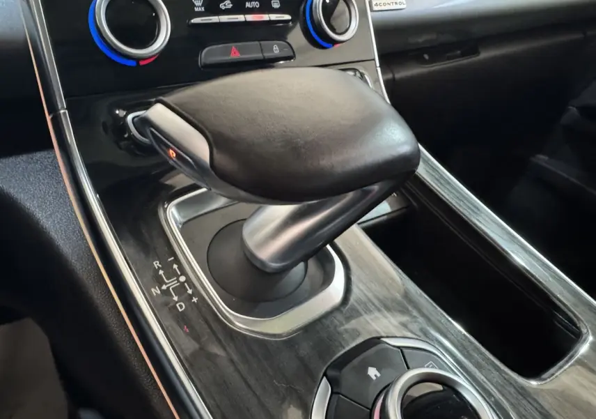 Gros plan sur la commande de boîte automatique en cuir noir et console en finition bois sombre du Renault Espace 2015.