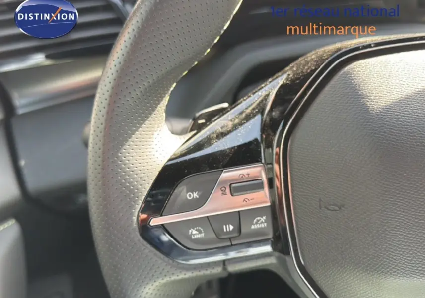 Gros plan sur le volant cuir perforé de la Peugeot 408 1.2 Hybrid 2025 avec commandes intégrées côté gauche.