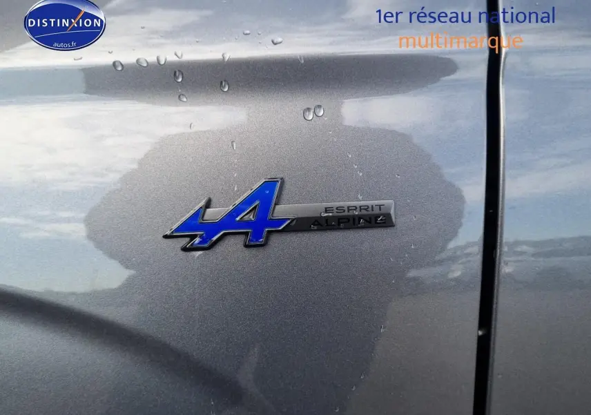 Gros plan sur l'écusson Esprit Alpine bleu sur la carrosserie gris schiste du Renault Espace VI hybride 2025