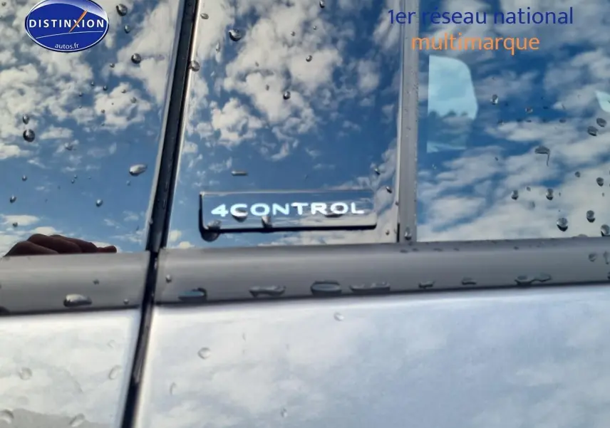 Gros plan sur l’inscription 4CONTROL sur la porte côté gauche d’un Renault Espace VI gris schiste sous la pluie.