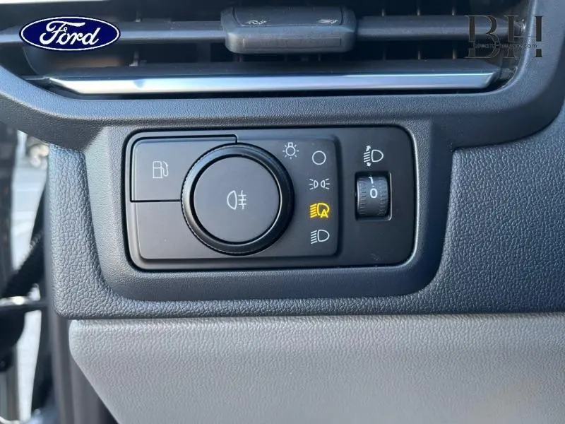 Gros plan sur le panneau de commande des phares du Ford Transit Custom gris, avec bouton rotatif et réglage de luminosité.