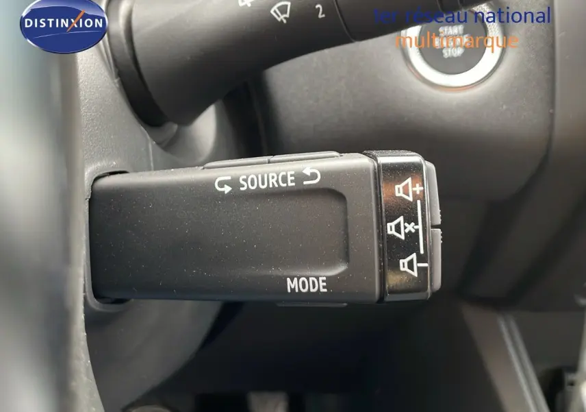 Gros plan sur la commande au volant du Renault Captur E-Tech gris cassiopée, avec boutons source et mode visibles.