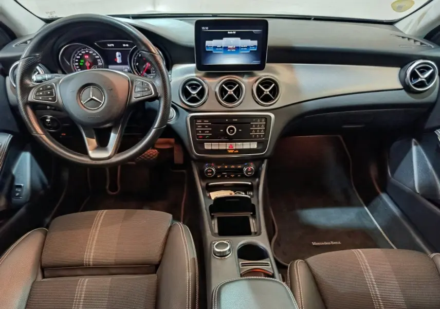 Vue intérieure avant du Mercedes GLA 200 d gris clair, tableau de bord moderne avec écran central et volant cuir multifonctions.