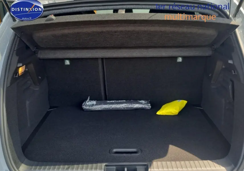 Coffre ouvert d'un Renault Captur gris rafale, montrant un espace de rangement avec tapis noir et deux accessoires.