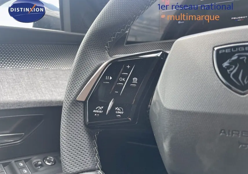 Gros plan sur le volant en cuir perforé noir du Peugeot 5008 Hybrid 2025, avec commandes intégrées côté gauche.