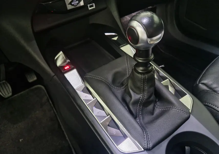 Le levier de vitesses manuel en cuir noir du DS3 Crossback 2022, avec boutons de commande argentés autour.
