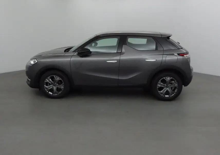 Profil côté gauche d'un DS3 Crossback gris platinium 2022, avec lignes sculptées et toit noir contrastant.