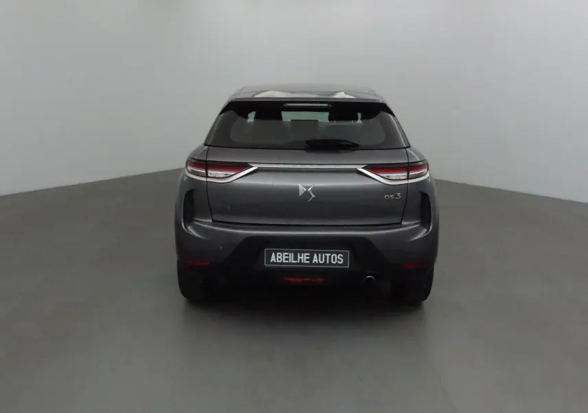 Vue arrière d'un DS3 Crossback gris platinium 2022 avec feux LED et logo DS bien visibles sur fond neutre.