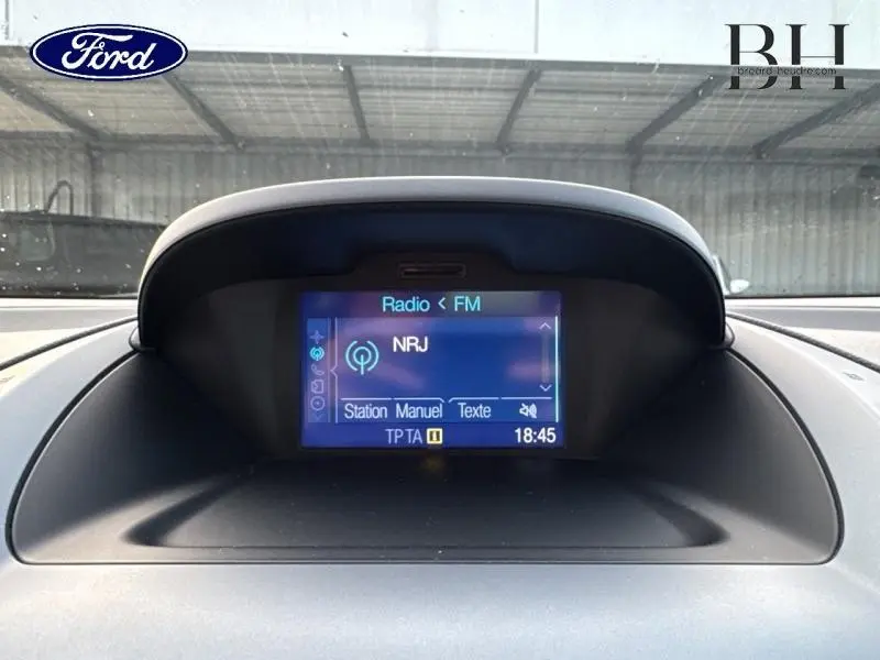 Écran tactile central affichant la radio NRJ dans l'habitacle d'une Ford B-MAX blanc glacier, vue de face rapprochée.