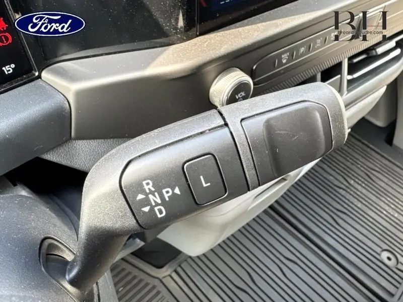 Gros plan sur la commande de boîte automatique du Ford Transit Custom 2025, avec tableau de bord et molette de volume visibles.