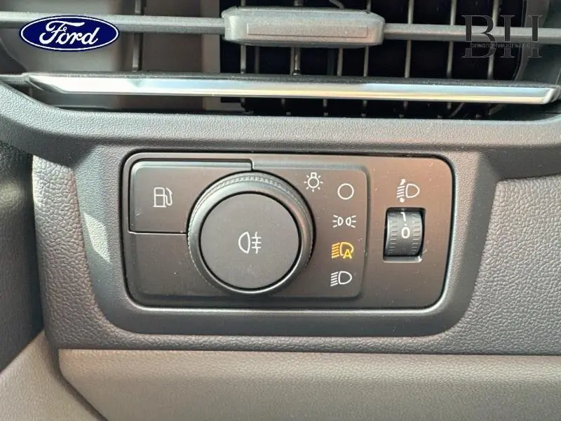 Gros plan sur le panneau de commande des phares du Ford Transit Custom bleu azur, avec réglage automatique activé.