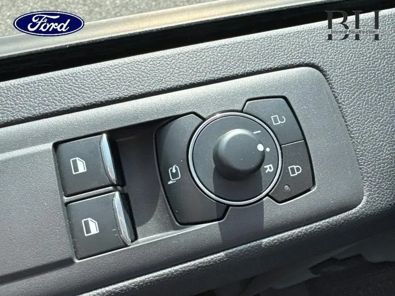 Gros plan sur les commandes de réglage des rétroviseurs et des vitres côté conducteur du Ford Transit Custom bleu azur métallisé.