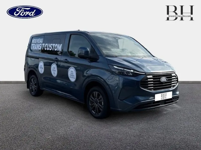 Ford Transit Custom Fourgon bleu azur métallisé en 3/4 avant droit avec marquages publicitaires sur la porte latérale.