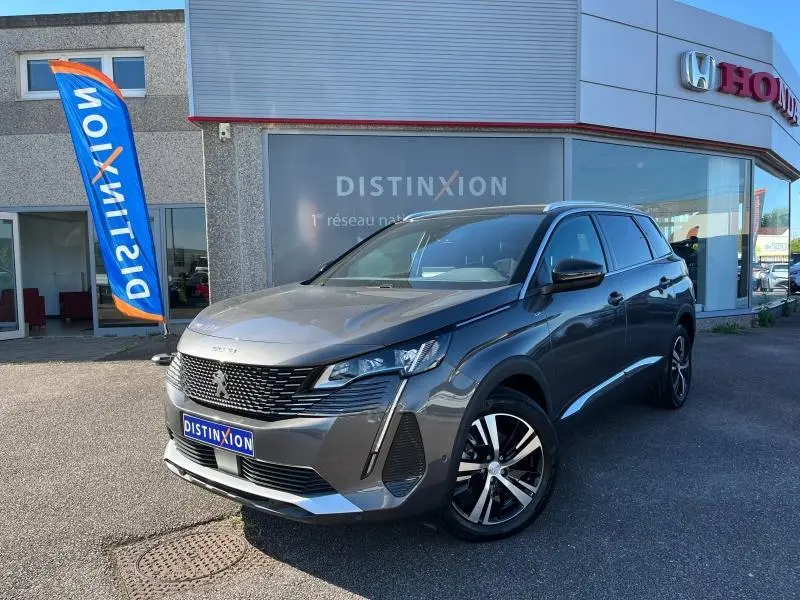 Peugeot 5008 gris Artense vue 3/4 avant droit, avec calandre noire et jantes alliage bicolores.