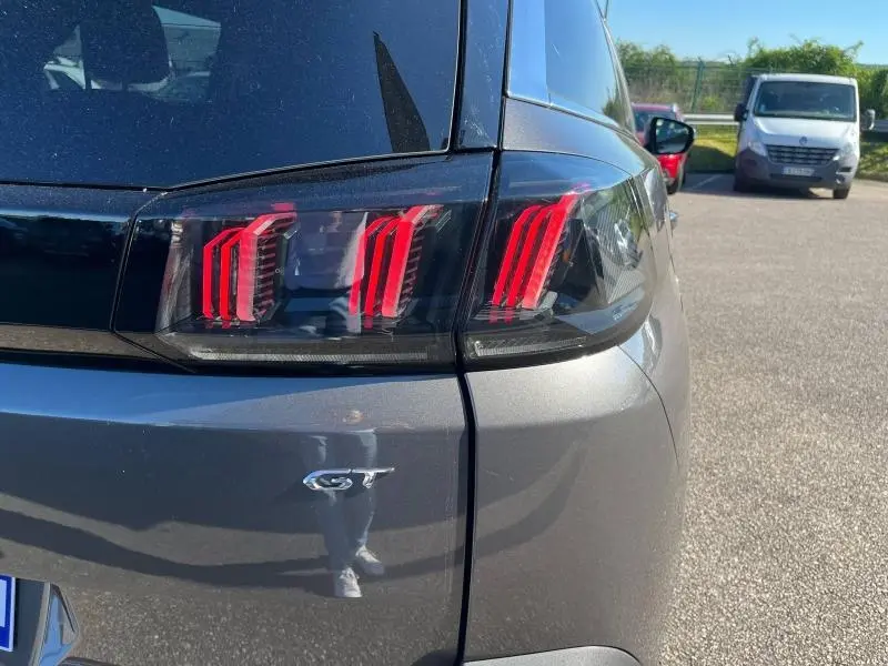Gros plan sur le feu arrière droit rouge du Peugeot 5008 gris Artense avec logo GT visible sur le hayon.