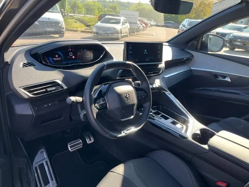 Intérieur avant du Peugeot 5008 2024 gris, volant cuir multifonction, tableau de bord numérique et écran tactile central.