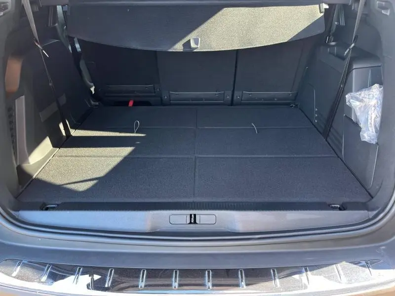 Coffre ouvert du Peugeot 5008 gris, vue de l'arrière montrant l'espace de chargement plat et les finitions intérieures noires.