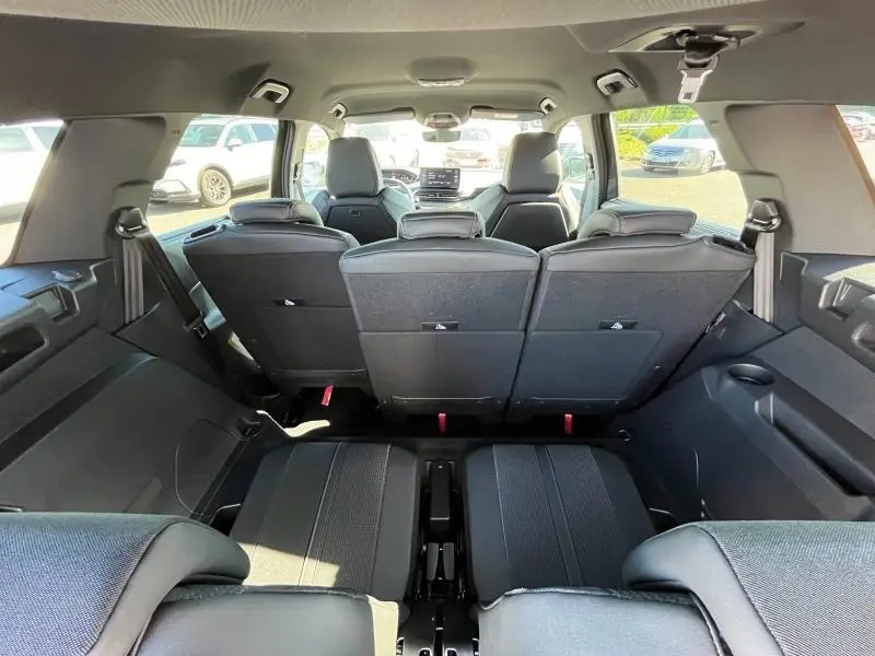 Vue arrière intérieure du Peugeot 5008 gris, montrant les sièges rang 2 et 3 avec tablette et appuis-tête.