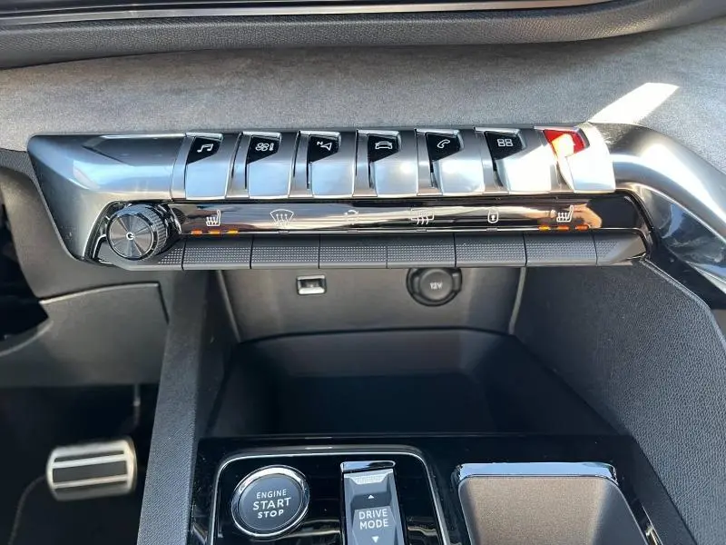 Tableau de bord du Peugeot 5008 gris 2024, avec commandes piano chromées et bouton start/stop visibles en gros plan.