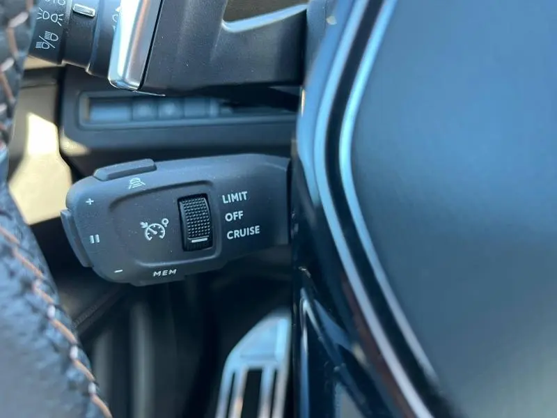 Gros plan sur la commande de régulateur de vitesse à gauche du volant du Peugeot 5008 gris 2024.