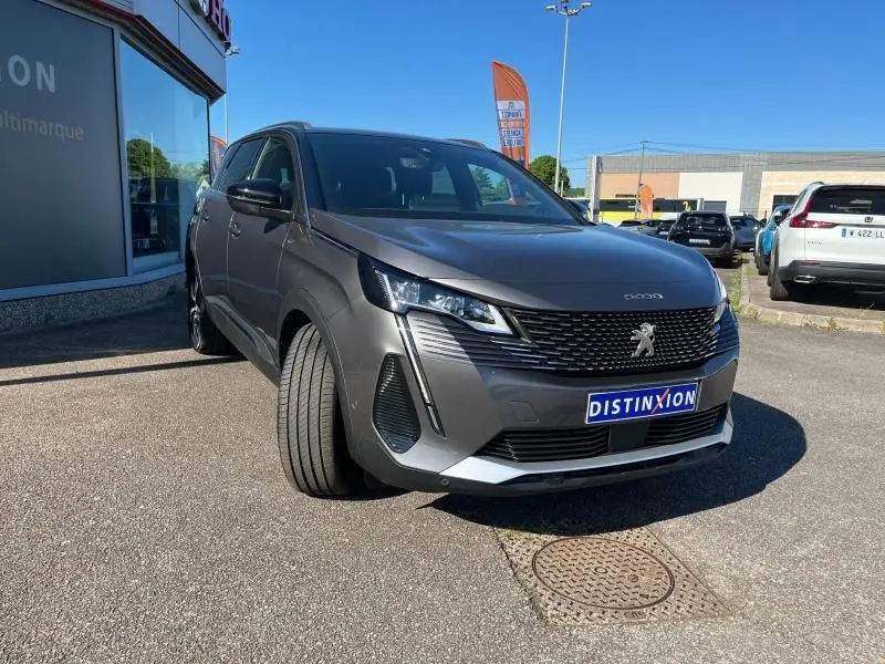 Peugeot 5008 gris Artense vue 3/4 avant droit, avec calandre noire et phares LED, stationnée en extérieur.