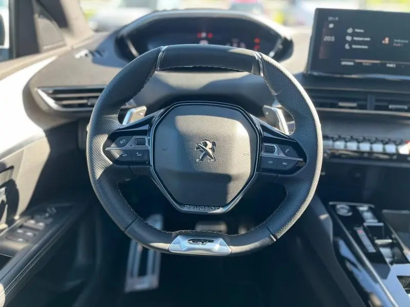 Volant cuir noir perforé Peugeot 5008 2024 GT avec commandes multifonctions et palettes au volant, vue de face intérieure.