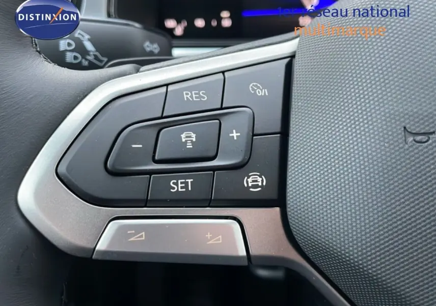 Gros plan sur les commandes au volant du Volkswagen T-Roc noir Grenadilla, mettant en valeur les boutons de régulateur de vitesse.