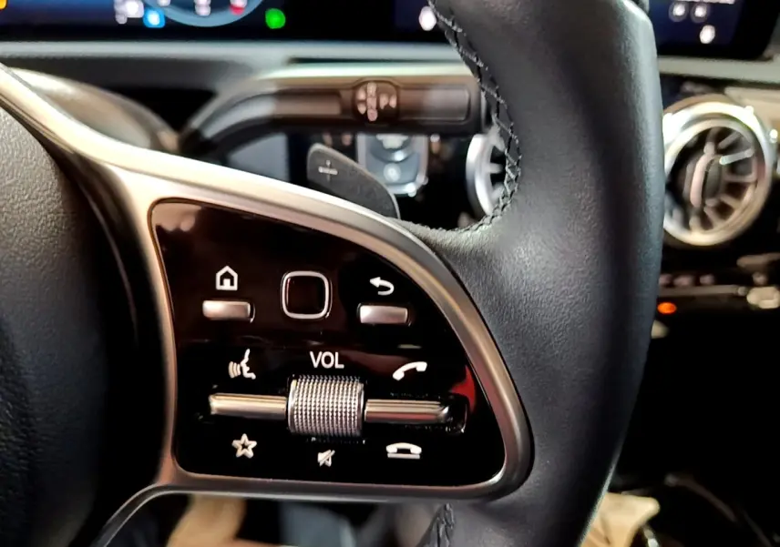 Gros plan sur les commandes multifonctions en cuir noir du volant de la Mercedes Classe A Berline A 200 d 2022.