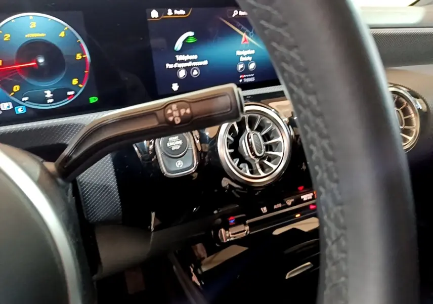 Vue rapprochée du tableau de bord noir de la Mercedes Classe A 200 d, avec écran tactile et aérateurs ronds chromés.