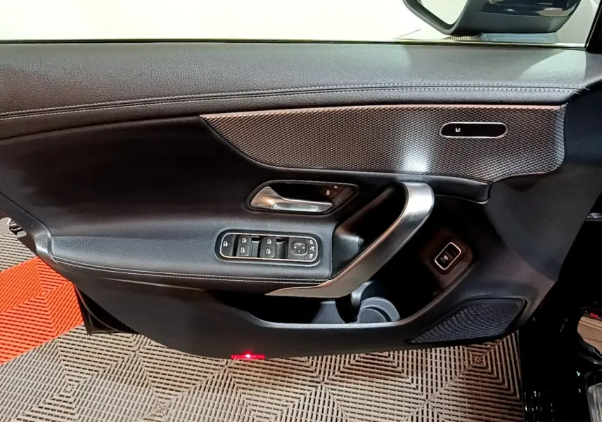 Vue rapprochée de la porte avant gauche noire de la Mercedes Classe A 200 d avec commandes électriques et insert décoratif.
